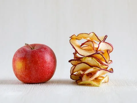 Dried thin slices tower of apple fruit chips and whole fruit on light backgro Stock Photos