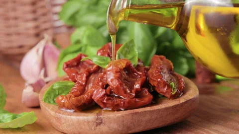 Dried tomatoes in olive oil, basil next to the bowl. Leaking oil. Traditional Video stock 196277367