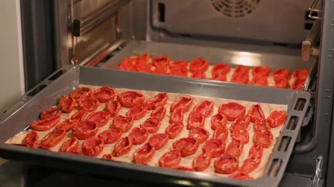Dried tomatoes on an oven tray. The process of preparing an Italian appetizer Stockbeeldmateriaal 212949211