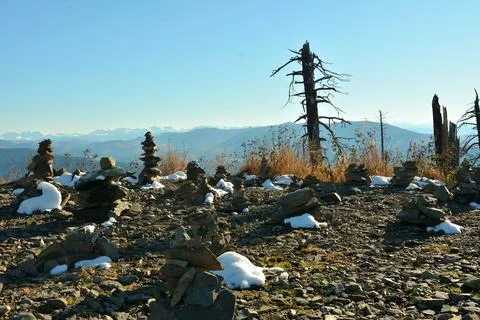 A dried tree trunk and stone pyramids covered with first snow on top of a c.. Stock Photos