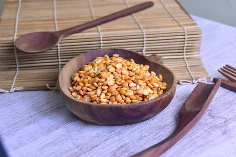 Dried yellow split peas inside wooden bowl on the side of sushi roller spoo.. Foto stock