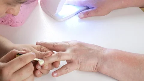 Dries nails in a UV lamp with LEDs.Master applies yellow gel polish. Stock-Footage 138790754
