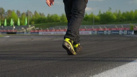 Drift competitions, A pilot in a jumpsuit walks along a race track at sunset Stock Footage 335812536