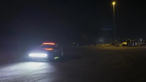 Drifting car performing donuts and power slides in dark parking lot at nigh.. Stock-Footage 339386933