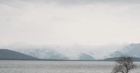 Drifting clouds cast their reflection on Lake Sevan's calm waters. The lake, a Видео 252467470