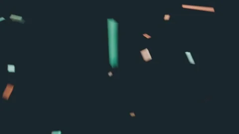 Drifting confetti rotating and falling in dark studio, camera shift revealing Stock Footage 337504980