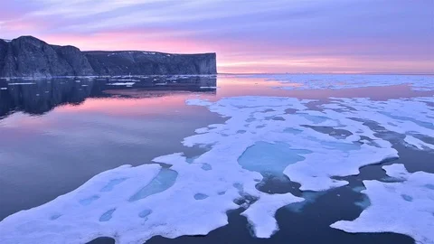 Drifting past sea ice under the midnight sun on Scott Island off Baffin Island Stock Footage