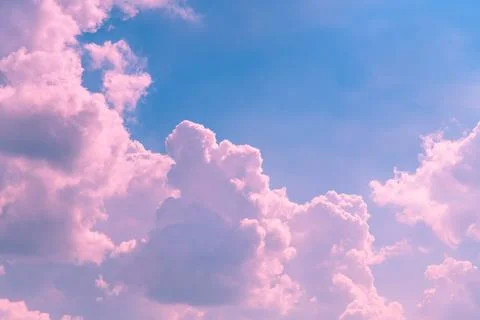 Drifting pink clouds float across a vibrant blue sky, crafting a dreamy and.. Stock Photos