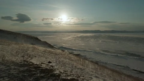 Drifting snow spreads over the surface of Baikal Lake blown by the wind 動画素材 232378645