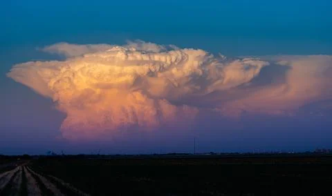 Drifting storm clouds reflect vibrant sunset colors, creating a dramatic sky  Stock Photos