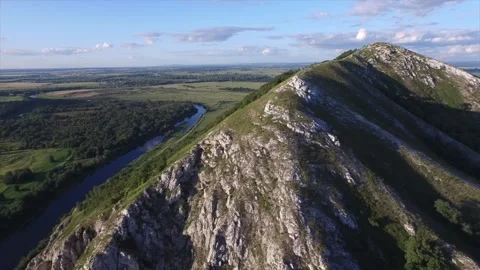 A drifting view of a rocky mountain from a drone, a hill surrounded by a river Stock Footage 130642962