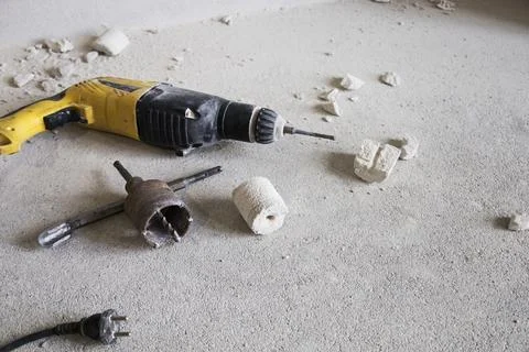 A drill and a wrench are currently laying on the floor nearby Stock Photos