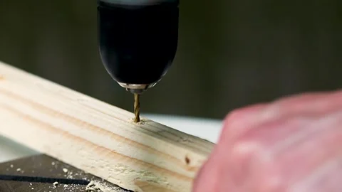 The drill bit drills a wooden block. Male hand. Close-up. Stock Footage 245986139