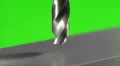 The drill bit make a hole in the aluminium surface on a green background HD Footage