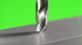The drill bit make a hole in the aluminium surface on a green background HD Footage