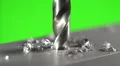 The drill bit make a hole in the aluminium surface on a green background HD Footage
