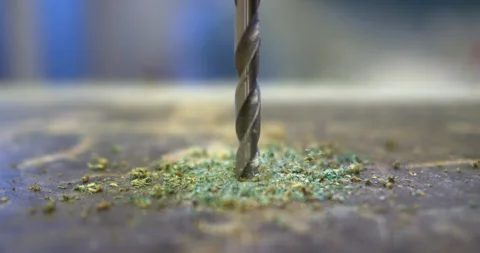 Drill bit piercing through material creating green dust Video stock 303045329