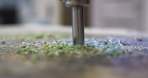 Drill bit piercing through material creating green dust Stock Footage 303626158