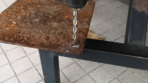 The drill bit is rotating to punch holes in the rusted iron plate. Stock Footage 121305359
