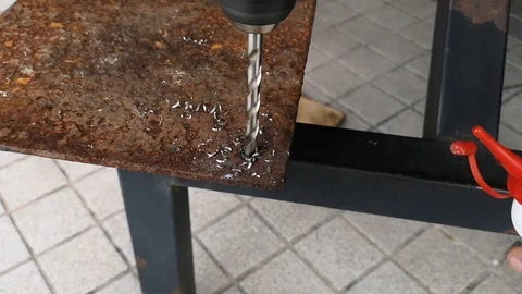 The drill bit is rotating to punch holes in the rusted iron plate. Stock Footage 121305398