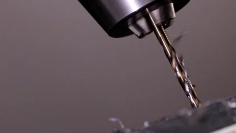 Drill Bit Spinning and Cutting Through a Metal Workpiece Stock Footage 304767443