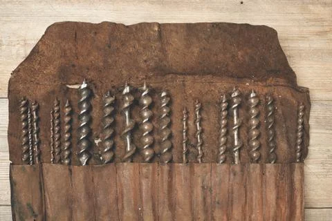 Drill bits in leather tool roll on a wooden workbench Stock Photos