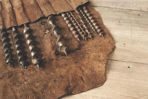 Drill bits in leather tool roll on a wooden workbench Stock Photos
