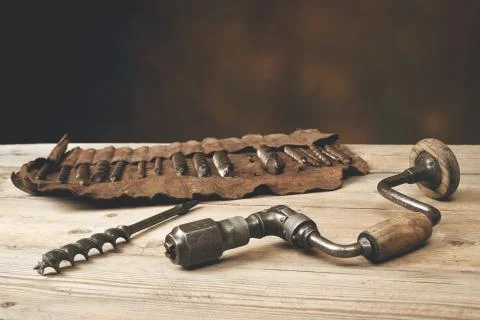 Drill brace with bits in leather tool roll on a wooden workbench Stock Photos