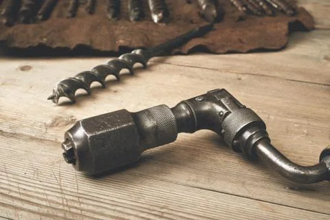 Drill brace with bits in leather tool roll on a wooden workbench Stock Photos