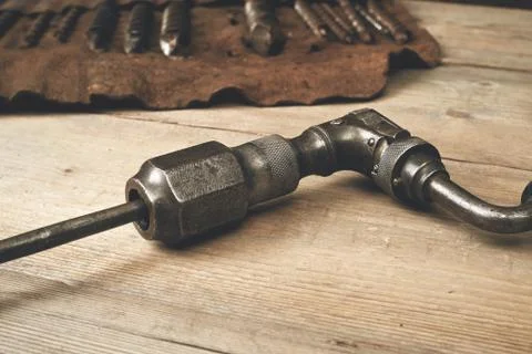 Drill brace with bits in leather tool roll on a wooden workbench Stock Photos