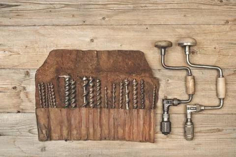 Drill braces with bits in leather tool roll on a wooden workbench Stock Photos