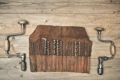 Drill braces with bits in leather tool roll on wooden workbench Stock Photos