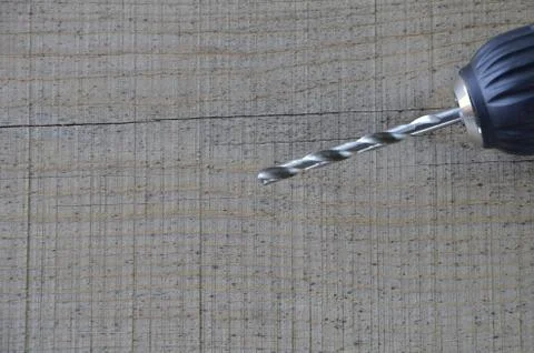 Drill Chuck with a drill bit on the background of a wooden table. Stock Photos