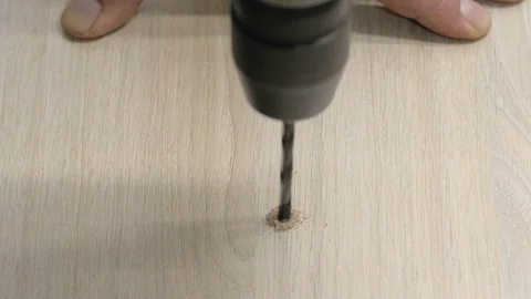 Drill wood board. Close up hands hold electric drill. Blowing wood dust Video stock 74667510