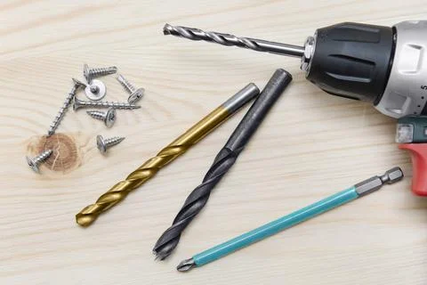 Drill on a wooden background. Self-tapping screws. Bits. Stock Photos