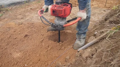 Drilling deep into dirt for post installation, professional operator creates Stock Footage 319403039