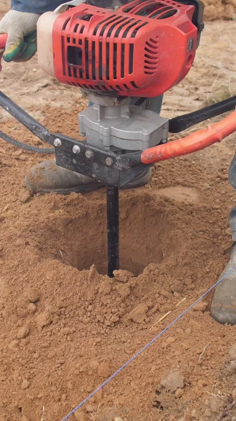 Drilling deep into dirt for post installation, professional operator creates Stock Footage 319704849