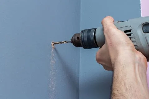 Drilling a gray wall with a drill close-up Stock Photos