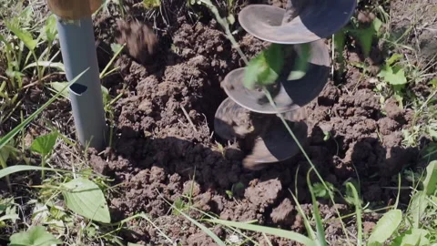 Drilling a hole in the ground for self-installation of the fence, close-up Stock Footage 156979836