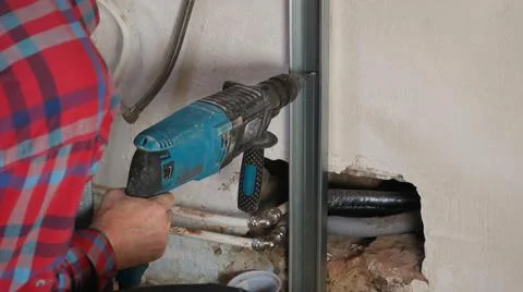 Drilling holes in the wall to secure the profiled metal. Stock Photos