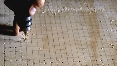Drilling a pattern of holes using a power tool and guided by grid lines. Stock Footage 108587998