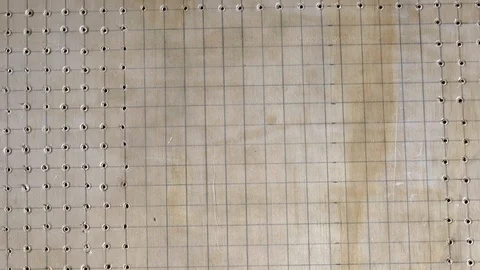 Drilling a pattern of holes using a power tool and guided by grid lines. Stock Footage 108593501