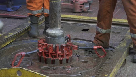 Drilling platform. Rotor table. Manual slips installed. Legs in orange coveralls Stock Footage 205384224
