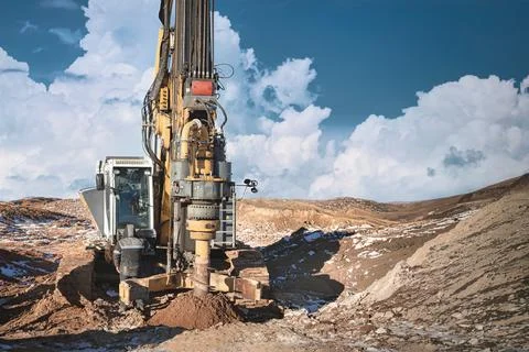 A drilling rig is in action, installing piles into rocky ground. The scene sh Stock Photos