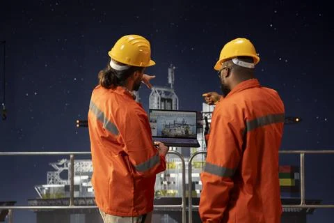 Drilling rig engineering team analyzing machinery performance on laptop Stock Photos