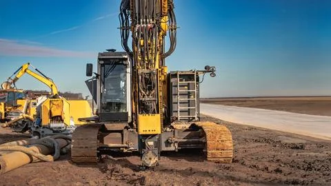 A drilling rig is operating on a construction site, driving piles into the gr Stock Photos