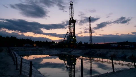Drilling rig &amp; a pond of Drilling fluid waste at dusk. Timelapse. Stock Footage 203790572