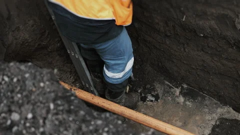 A drilling rig worker descends a ladder into a pit and checks the connection. Stock Footage 318270516