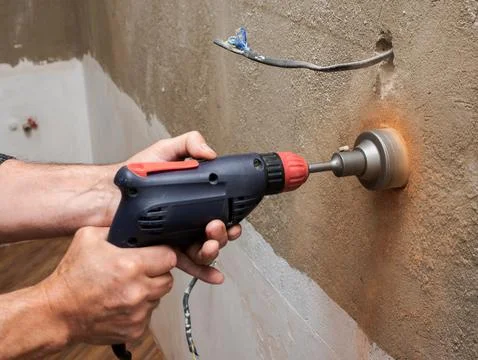 Drilling a socket in a brick wall, a drill for a socket, a worker doing ele.. Stock Photos