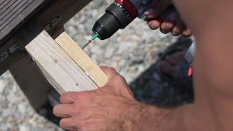 Drilling wood construction, man uses drill on lumber planks for outdoor building Stock Footage 321866914